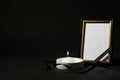 Funeral photo frame with ribbon and candle on black background Royalty Free Stock Photo