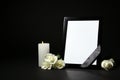 Funeral photo frame with ribbon, white roses and candle on dark table against black background Royalty Free Stock Photo