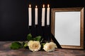 Blank funeral frame, candles and flowers on table against black background Royalty Free Stock Photo