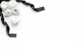 Funeral symbols. White flower near black ribbon on white background top view copy space