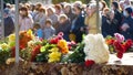 Funerary urn with ashes of dead and flowers at funeral. Burial urn decorated with flowers and people mourning in Royalty Free Stock Photo