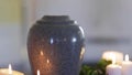 Funerary urn and candles on table burning indoors