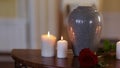 Funerary urn and candles on table burning indoors
