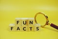 Funfacts with wooden blocks alphabet letters and Magnifying glass on yellow background Royalty Free Stock Photo