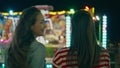 Funfair girls watching illuminated carousel rear view. Happy teenage friends Royalty Free Stock Photo