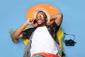 Funky black guy in trendy summer clothes lying on inflatable lilo, speaking on smartphone over blue background, top view Royalty Free Stock Photo