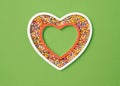 Funky flat lay white bordered heart with a pink bordered heart filled with neon colored small balls. Placed on pastel green