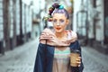 Funky hipster young girl tourist walking city streets holding to go coffee