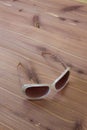 Funky pair of women sunglasses, white frame with rhinestones, neutral wood tabletop