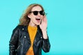 Funky stylish beautiful rocker Girl in leather jacket and black sunglasses. Punk is not dead. Attractive cool young woman shouting