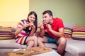 Funky young couple eating pizza on a couch