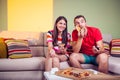 Funky young couple eating pizza on a couch Royalty Free Stock Photo