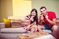 Funky young couple eating pizza on a couch Royalty Free Stock Photo