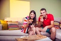 Funky young couple eating pizza on a couch Royalty Free Stock Photo