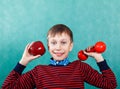 Funny active schoolboy excercising holding an apple and a dumbbell