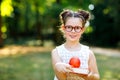 Funny adorable little kid girl with glasses, book, apple and backpack on first day to school or nursery. Child outdoors Royalty Free Stock Photo