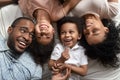 Funny affectionate african parents and kids laughing lying on bed Royalty Free Stock Photo