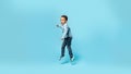 Funny african american little boy jumping in air, fooling around over blue background, full length, panorama, free space Royalty Free Stock Photo