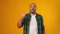 Funny African American man came up with an idea with raised finger against yellow background