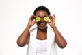 Funny african woman holding kiwi halves in front of eyes