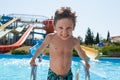 Funny aggressive sport little caucasian kid near blue pool in summer amusement aqua park in sunny leisure day