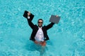 Funny amazed businessman in suit with laptop in swimming pool. Crazy excited business man on summer vacation. Excited