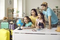 Funny amazed family with children finding location for travel on earth globe