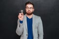 Funny amazed young businessman in glasses holding small light bulb