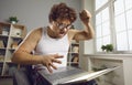 Funny nerdy man having problem with his laptop, shouting and threatening to break it