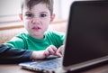 Funny angry little boy using laptop, close-up Royalty Free Stock Photo