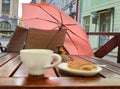 Tourism in Europa Street cafe table with cup of coffee umbrella   on chair and sparrow sit on table eating sweet cake travel to Eu Royalty Free Stock Photo