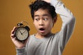 Funny Asian boy awake and shocked because it is too late, young student boy worried to see clock Royalty Free Stock Photo