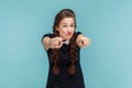 Funny attractive young woman with braids pointing at you, looking at camera with frowning face. Royalty Free Stock Photo