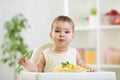 Funny baby eating healthy food in kitchen Royalty Free Stock Photo