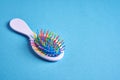 Funny baby comb with multi-colored plastic wavy bristles lies on a blue background