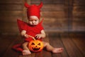 Funny baby in devil halloween costume with pumpkin Royalty Free Stock Photo