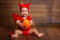 Funny baby in devil halloween costume with pumpkin Royalty Free Stock Photo
