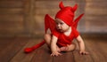 Funny baby in devil halloween costume on wooden background Royalty Free Stock Photo