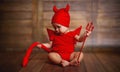 Funny baby in devil halloween costume on wooden background Royalty Free Stock Photo