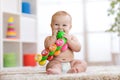 Funny baby in diaper sits on carpet and plays with toy at home. Shallow depth of field.