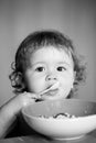 Funny baby eating food himself with a spoon on kitchen. Child nutrition concept. Funny child face closeup. Royalty Free Stock Photo