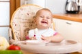 Funny baby eating in high-chair on kitchen Royalty Free Stock Photo