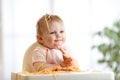 Funny baby eating noodle. Grimy kid eats spaghetti with handssitting on table at home Royalty Free Stock Photo