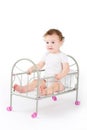 Funny baby girl playing in a doll bed Royalty Free Stock Photo