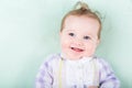 Funny baby girl in purple dress lying on green knitted blanket Royalty Free Stock Photo