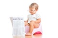 Funny baby girl reading newspaper on chamberpot Royalty Free Stock Photo