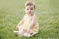 Funny baby kid with toy. Cute adorable baby girl in yellow dress sitting on grass in park outdoors. Funny child toddler playing Royalty Free Stock Photo