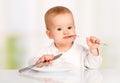 Funny baby with a knife and fork eating food