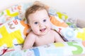 Funny baby playing peek-a-boo under colorful blanket