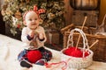 Funny baby sitting with a ball of red thread on the background of a Christmas tree. concept of gift with your own hands Royalty Free Stock Photo